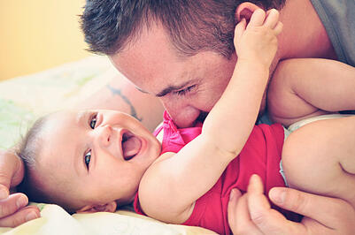 Father playing with his happy and smiling baby daughter